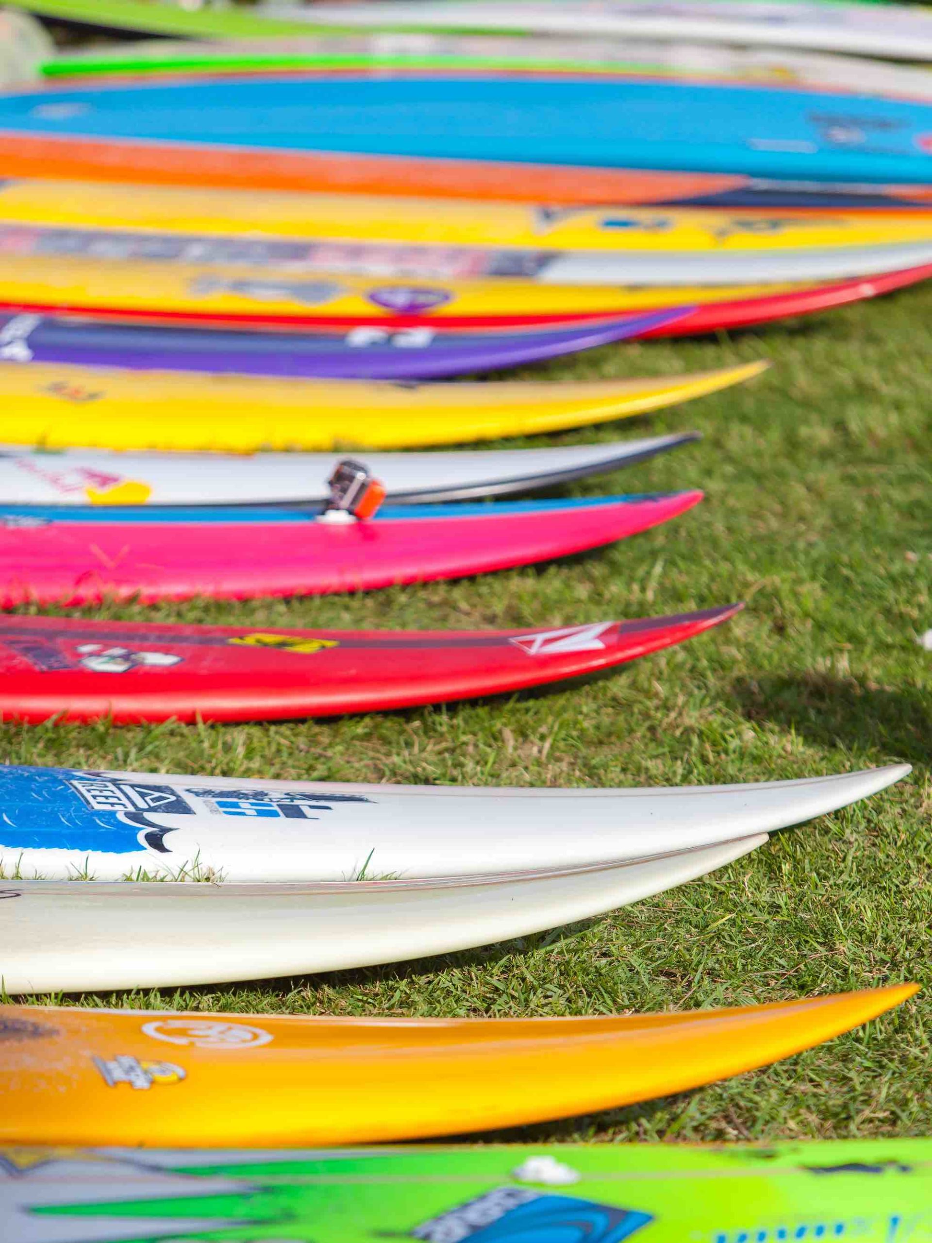 Find out all the best things to do in Haleiwa, Oahu. Image of a bunch of colorful surfboards on the grass in Oahu.