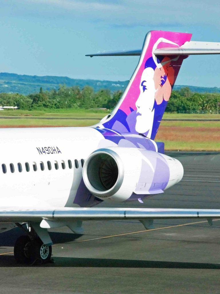 Find out how to go island hopping in Hawaii with tips from top Hawaii blog Hawaii Travel with Kids. Image of a Hawaiian Airlines airplane at Hilo Airport.