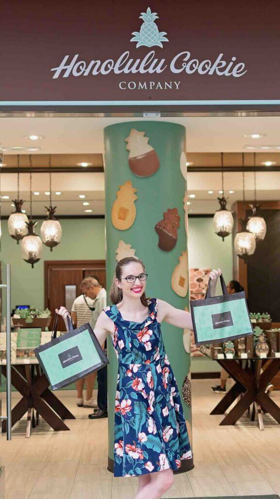 Enjoying Honolulu Cookie Company samples is one of my favorite free things to do Oahu. Image of a woman holding bags of Hawaiian cookies.