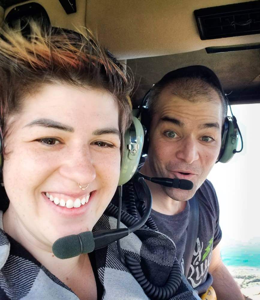 Find out all the best Kauai helicopter tour tips. Image of a man and woman taking a selfie during a doors off Kauai helicopter tour.