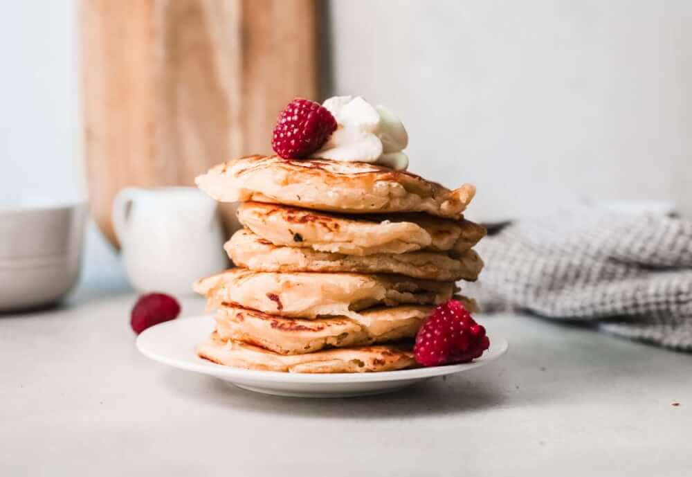 Learn how to make mochi pancakes by top Hawaii blog Hawaii Travel with Kids. Image of a plate of mochi pancakes topped with berries and whipped cream.