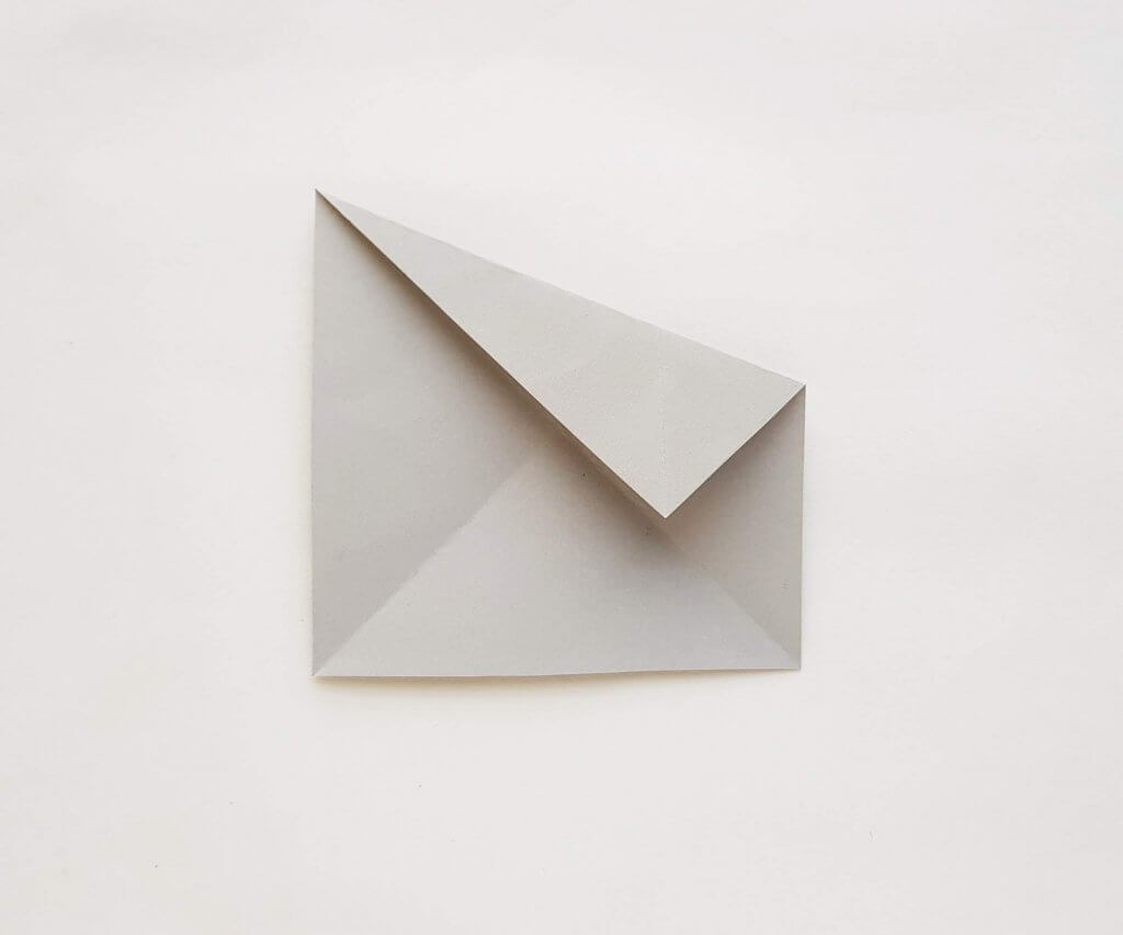 Find out how to make an origami shark for kids. Image of a grey piece of paper folded.