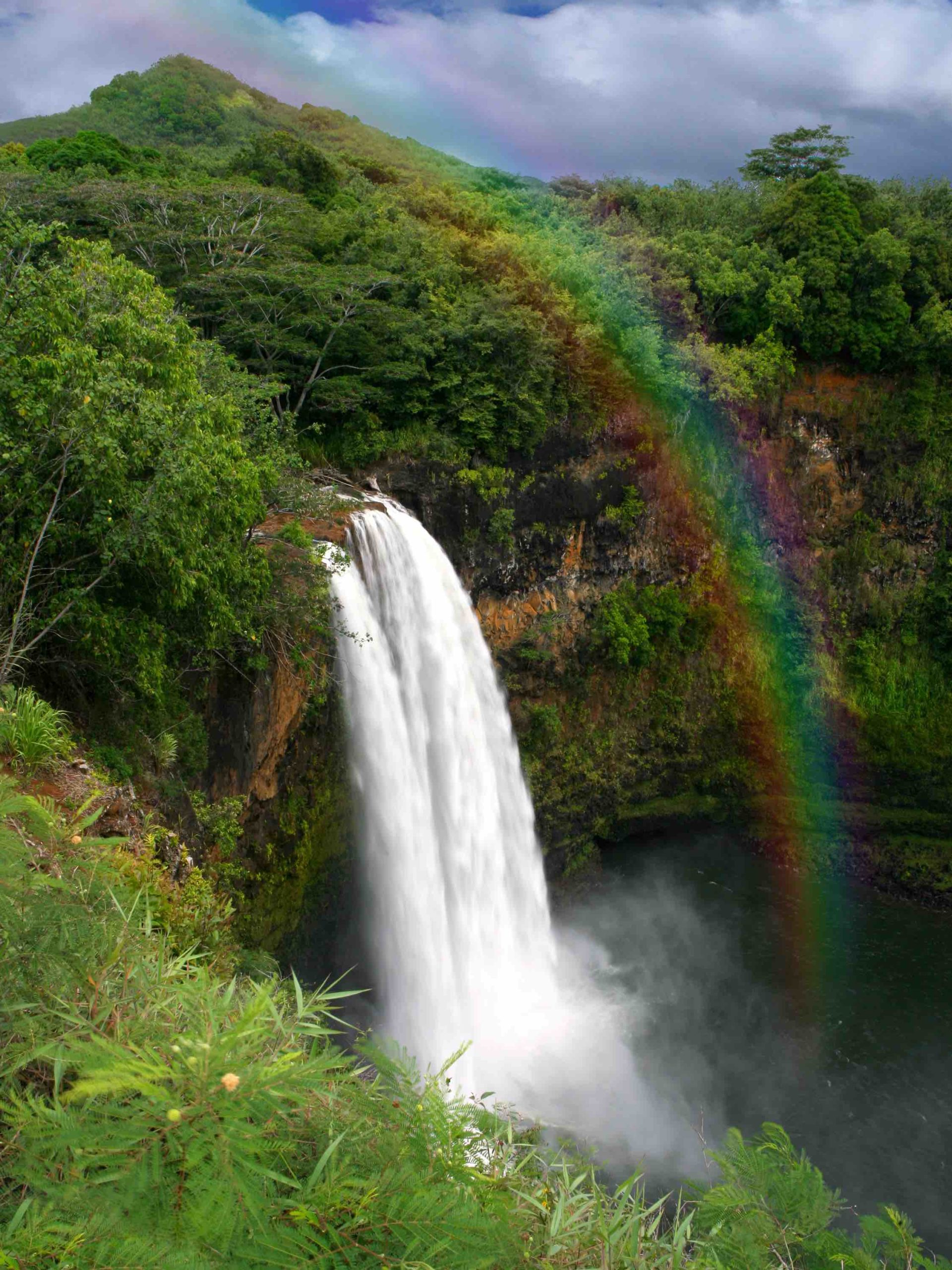 Find out all the best places to see in Hawaii by top Hawaii blog Hawaii Travel with Kids. Image of Waterfall in Hawaii With a Colorful Fantastic Rainbow