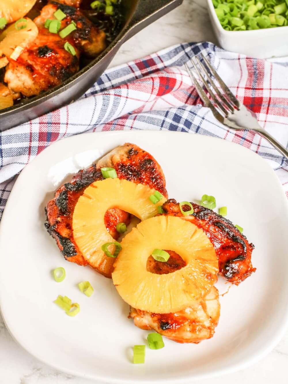 Learn how to make Skillet Pineapple Chicken from top Hawaii blog Hawaii Travel with Kids. Image of Hawaiian BBQ chicken topped with pineapple slices.