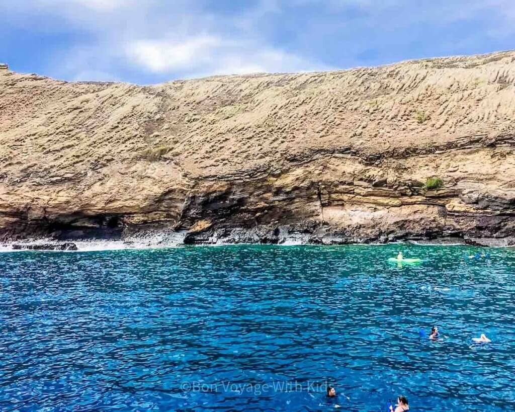 Find out the best Hawaiian island for snorkeling in this post by top Hawaii blog Hawaii Travel with Kids. Image of a bunch of people snorkeling in Hawaii off the coast of Molokini Crater Maui.