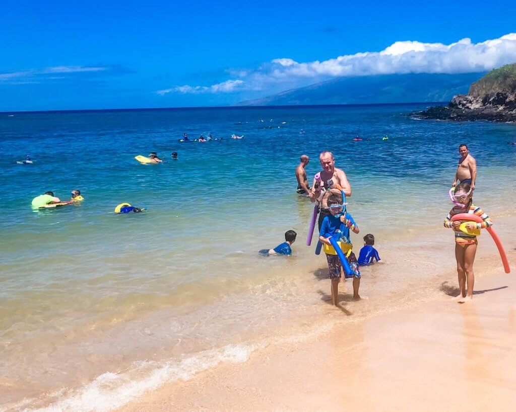 Find out all the best snorkeling Hawaii has to offer. Image of a family wearing snorkel gear and pool noodles.