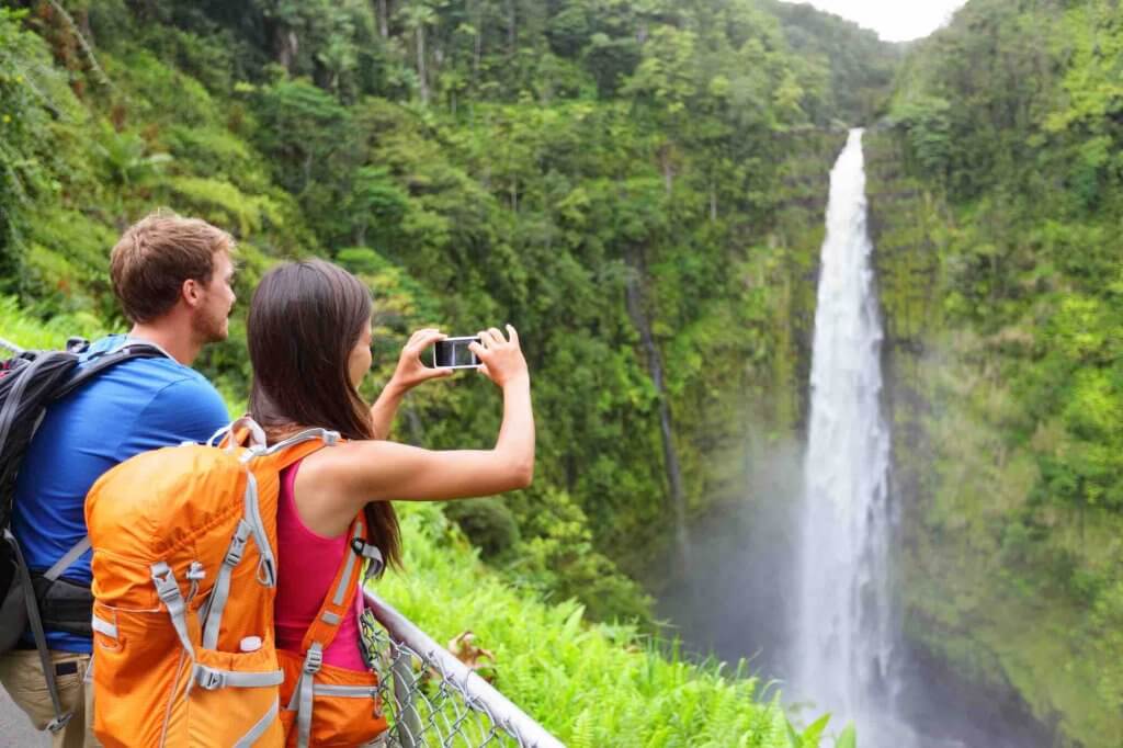 Find out the best things to do on the Big Island by top Hawaii blog Hawaii Travel with Kids.Image of a couple of tourists on Hawaii by waterfall.