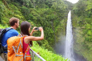 Find out my top Hawaii Big Island Vacation tips from top Hawaii blog Hawaii Travel with Kids.Image of a couple of tourists on Hawaii by waterfall.
