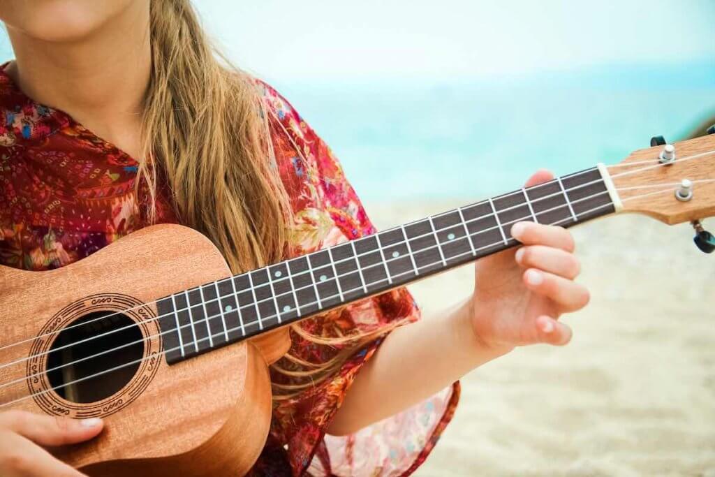 Find out where to hear live music in Maui. Image of a child playing the ukulele on the beach.