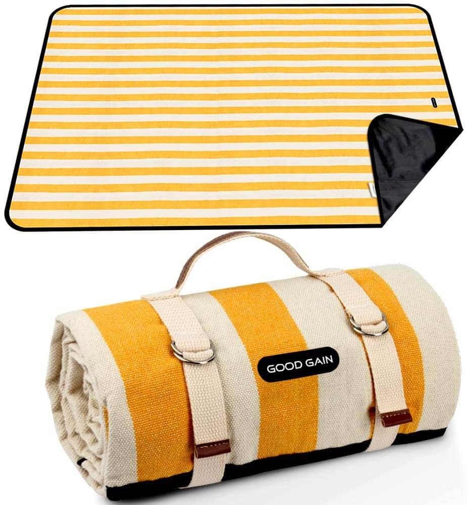 A waterproof and sandproof beach blanket is one of the smartest beach essentials for kids. Image of a white and yellow striped beach blanket. 