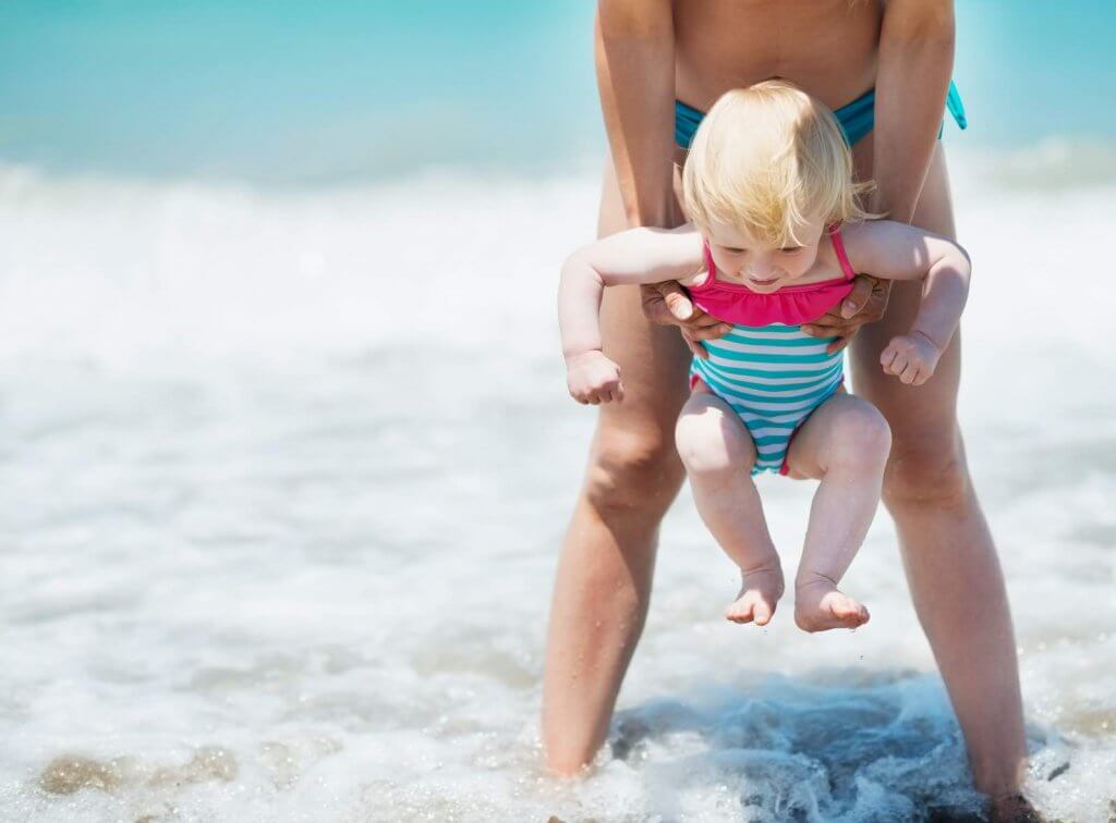 What are the top things to with babies in Hawaii? Image of Mother and baby playing with sea waves