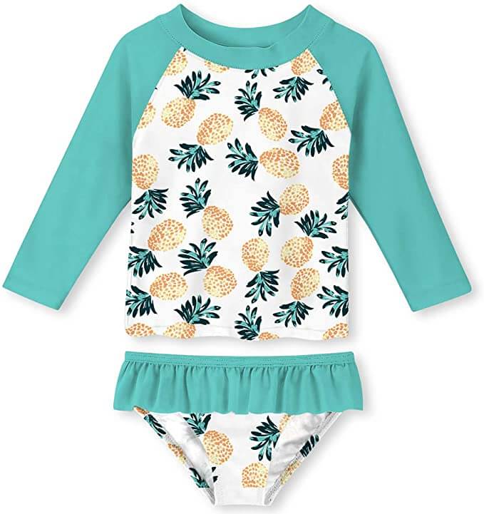 This pineapple print swimsuit is one of the cutest beach baby items. Image of a green and white swimsuit with yellow pineapples on it.