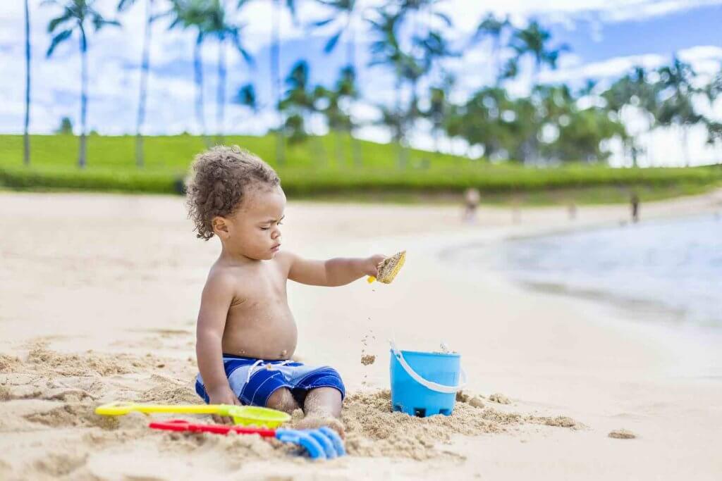 Find out the best things to do with toddlers in Hawaii by top Hawaii blog Hawaii Travel with Kids. Image of a toddler boy playing with sand toys.