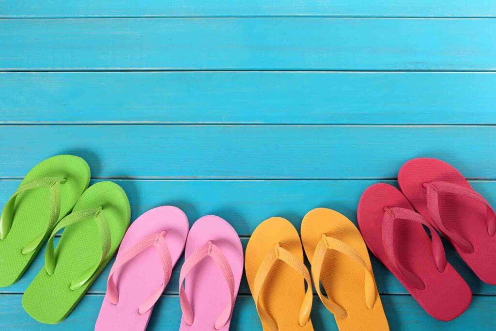 One of the coolest Hawaii culture facts is that people always remove their shoes before going in a house. Image of 4 pairs of flip flops on a blue deck.