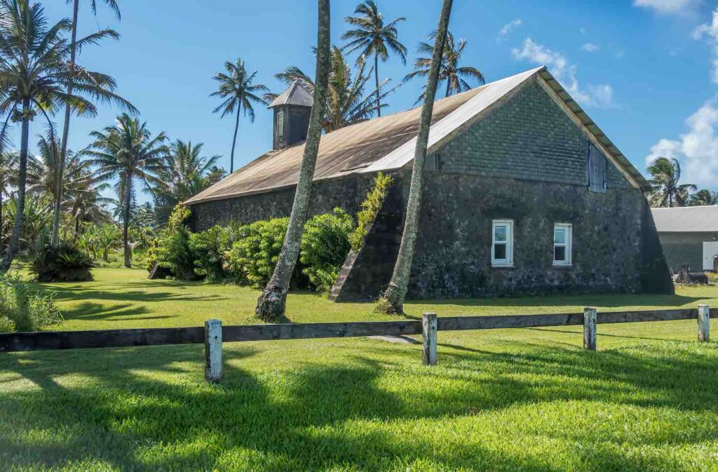 Another fun Road to Hana stop is the Keanae Point church on Maui. Image of a stone church surrounded by palm trees.