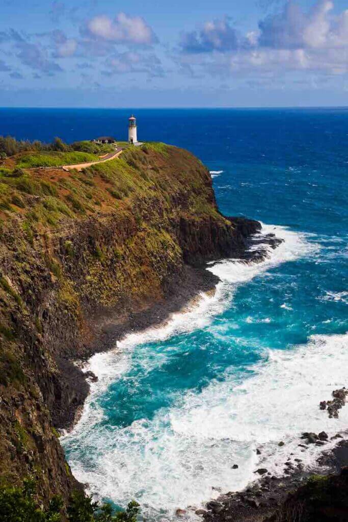 The Kilauea Lighthouse is a top Kauai attraction for families. Image of a lighthouse surrounded by blue ocean.