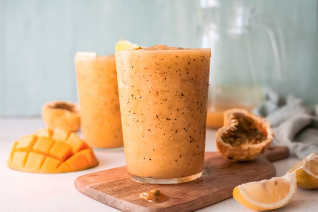 Learn how to make this mango passion fruit wine slushie by top Hawaii blog Hawaii Travel with Kids. Image of two glasses with tropical wine slushies surrounded by Hawaiian fruit.