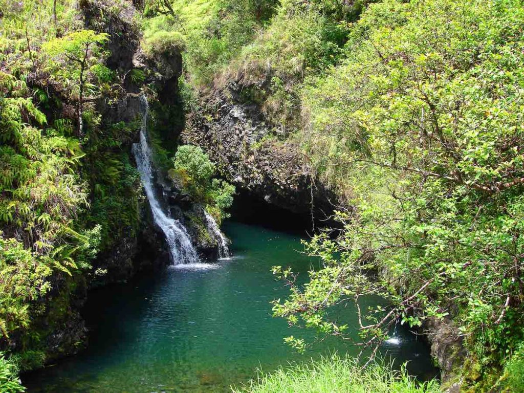 Find out the best Road to Hana stops for families by top Hawaii blog Hawaii Travel with Kids. Image of Waterfalls along the Road to Hana, Maui, Hawaii surrounded by lush greenery.