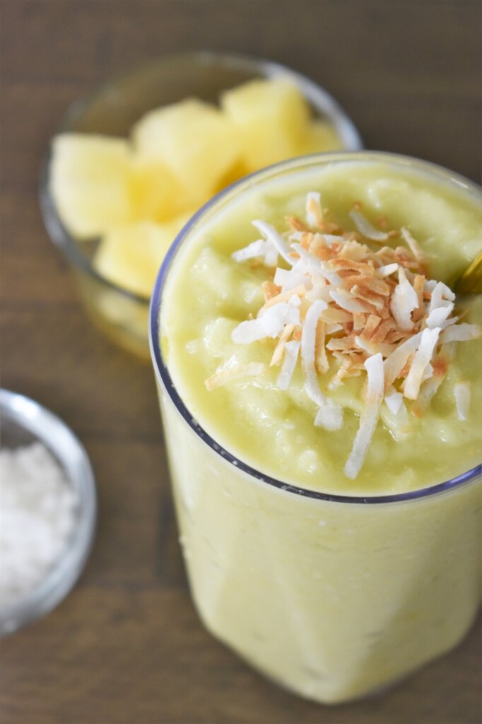 Learn how to make the pineapple avocado smoothie recipe by top Hawaii blog Hawaii Travel with Kids. Image of a tropical green smoothie topped with toasted coconut.