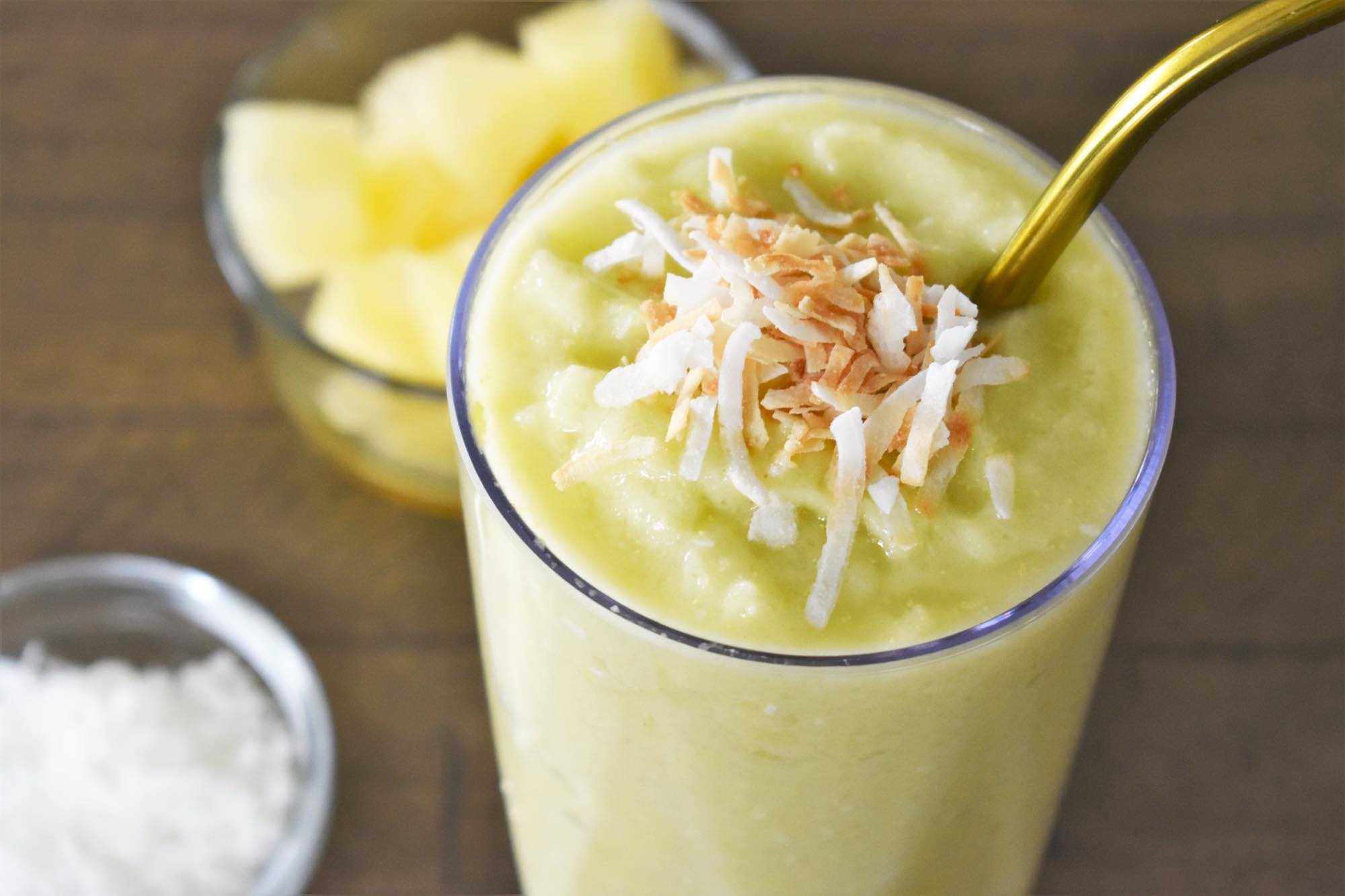 Learn how to make this easy avocado pineapple smoothie by top Hawaii blog Hawaii Travel with Kids. Image of a green smoothie topped with toasted coconut.