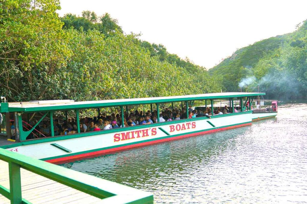 Take a Fern Grotto boat ride on this Wailua River tour before the Smith Family Luau. Image of a boat docked at the Wailua River.