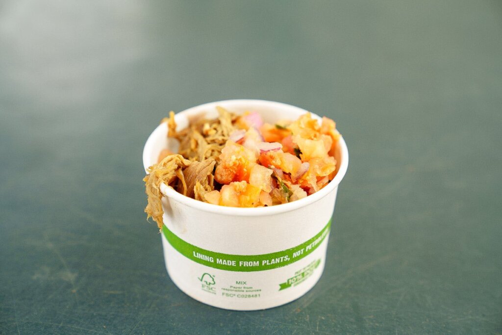 Image of a paper container filled with kalua pork, poi, and lomi lomi salmon.