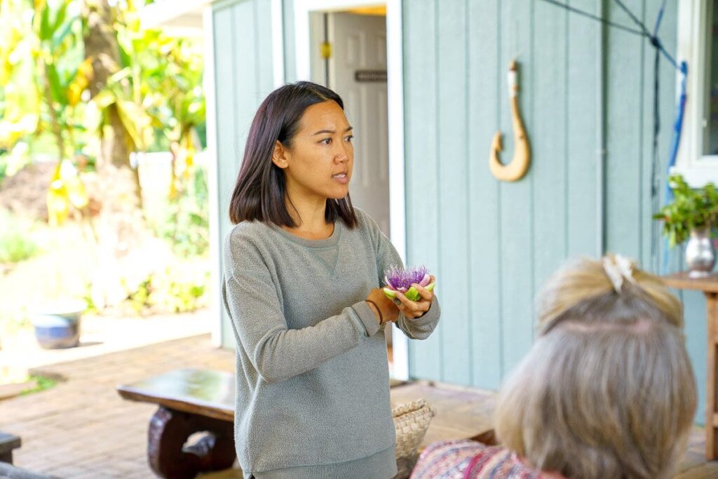 Image of a woman holding a Hawaiian plant at the Kauai Farmacy.