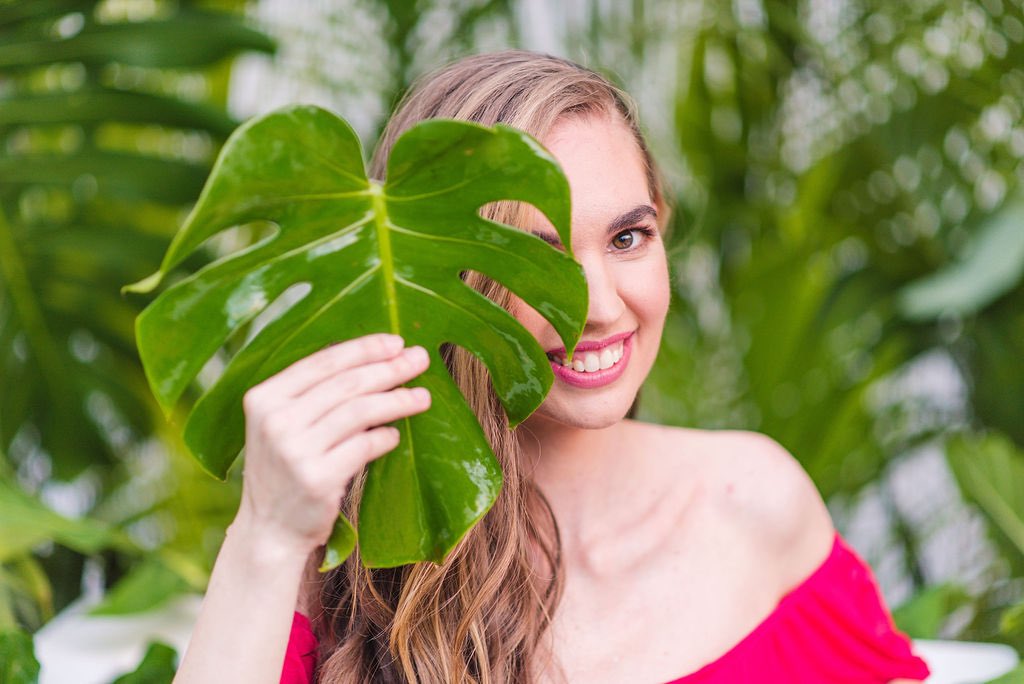 Image of a woman holding a monstera leaf in front of her eye at a Kauai photo shoot.