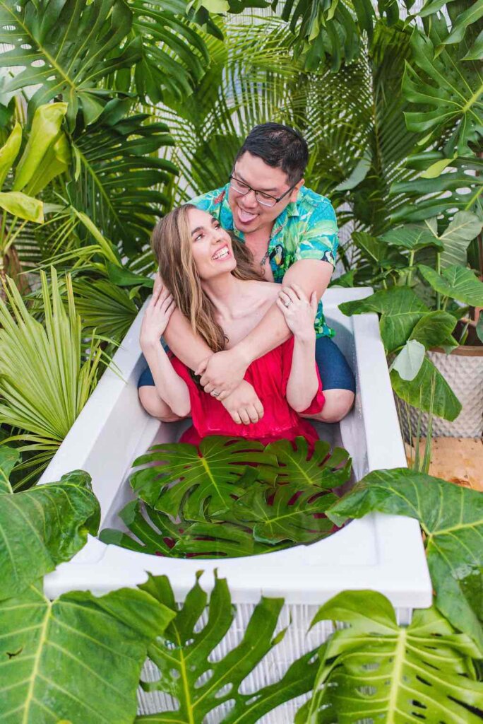 Image of a man and woman sitting in an outdoor Hawaiian bathtub fully clothed.