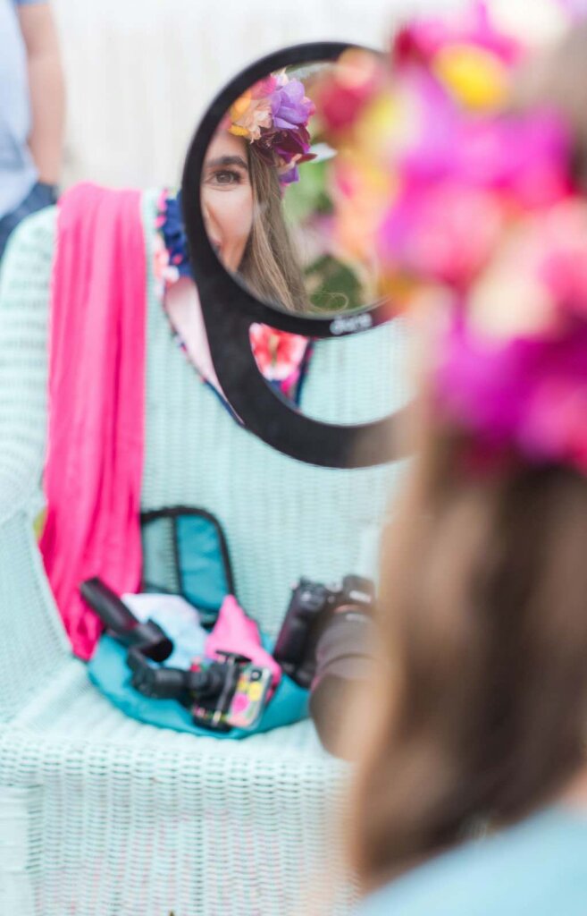 Image of a woman wearing a flower crown looking in a mirror before her photoshoot on Kauai.