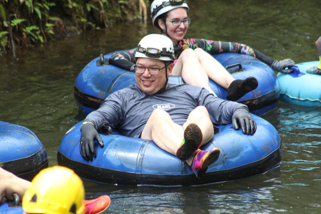 Find out what it's like to go mountain tubing on Kauai by top Hawaii blog Hawaii Travel with Kids. Image of a man and woman floating down a sugar cane canal on Kauai.