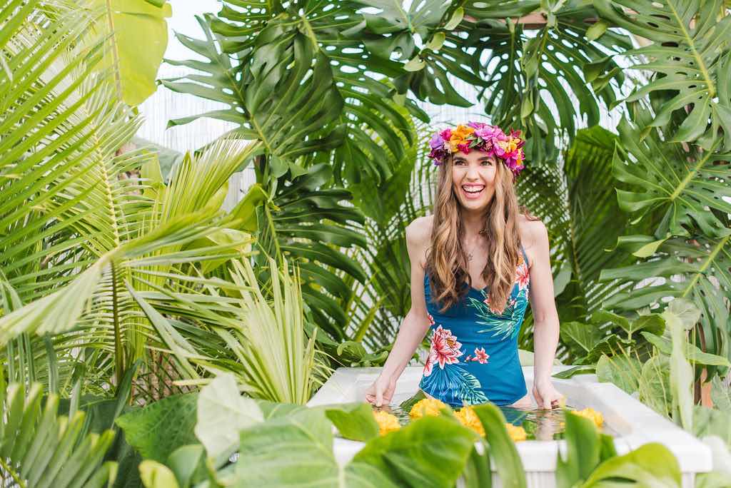 Bring along a cute swimsuit to your Kauai Jungle Tub photography session. Image of a woman wearing a floral swimsuit in an outdoor tropical bathtub.