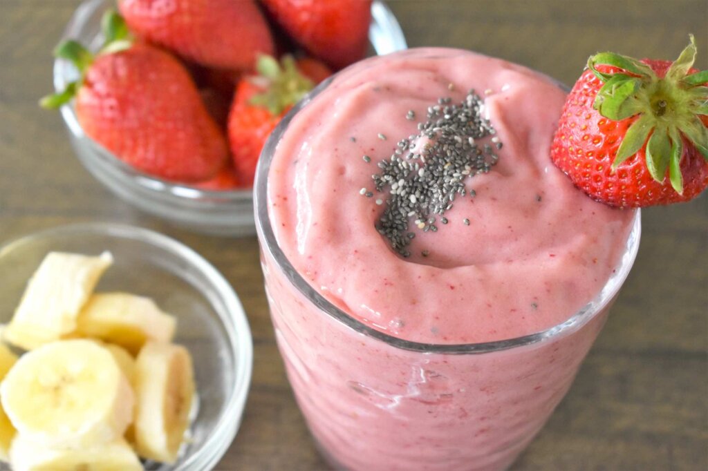 See how to make this Strawberry mango banana smoothie with chia seeds by top Hawaii blog Hawaii Travel with Kids. Image of a pink smoothie topped with chia seeds.