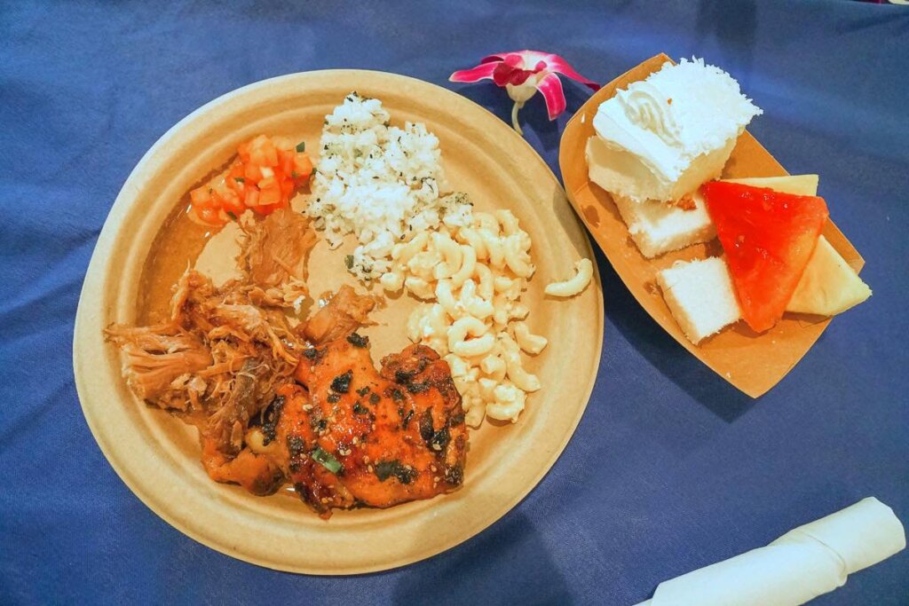 Toa Luau had some of the best luau food we're had in a long time. Image of a paper plate with teriyaki chicken, kalua pig, lomi loi salad, rice, macaroni salad, and dessert.