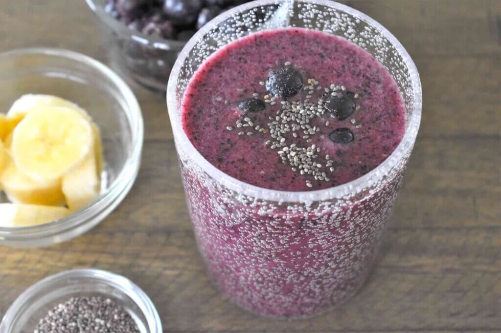 Learn how to make this blueberry banana chia smoothie with coconut water by top Hawaii blog Hawaii Travel with Kids. Image of a purple smoothie in a clear cup.