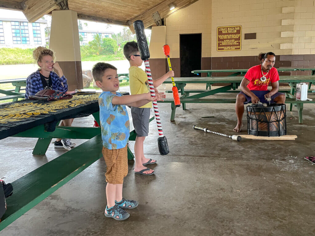 Image of two boys holding big sticks as they learn Hawaii fire dancing.