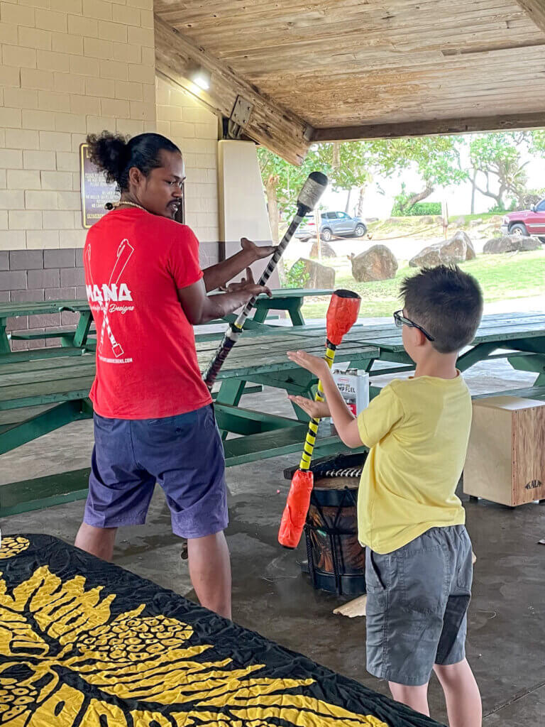 Image of a man teaching a kid how to do Samoan Fire Knife dancing on Kauai