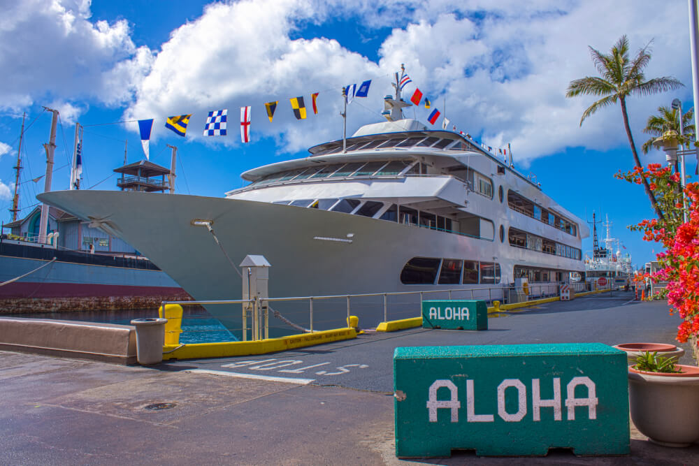 Image of a large white ship with a bunch of flags on it at Honolulu harbor