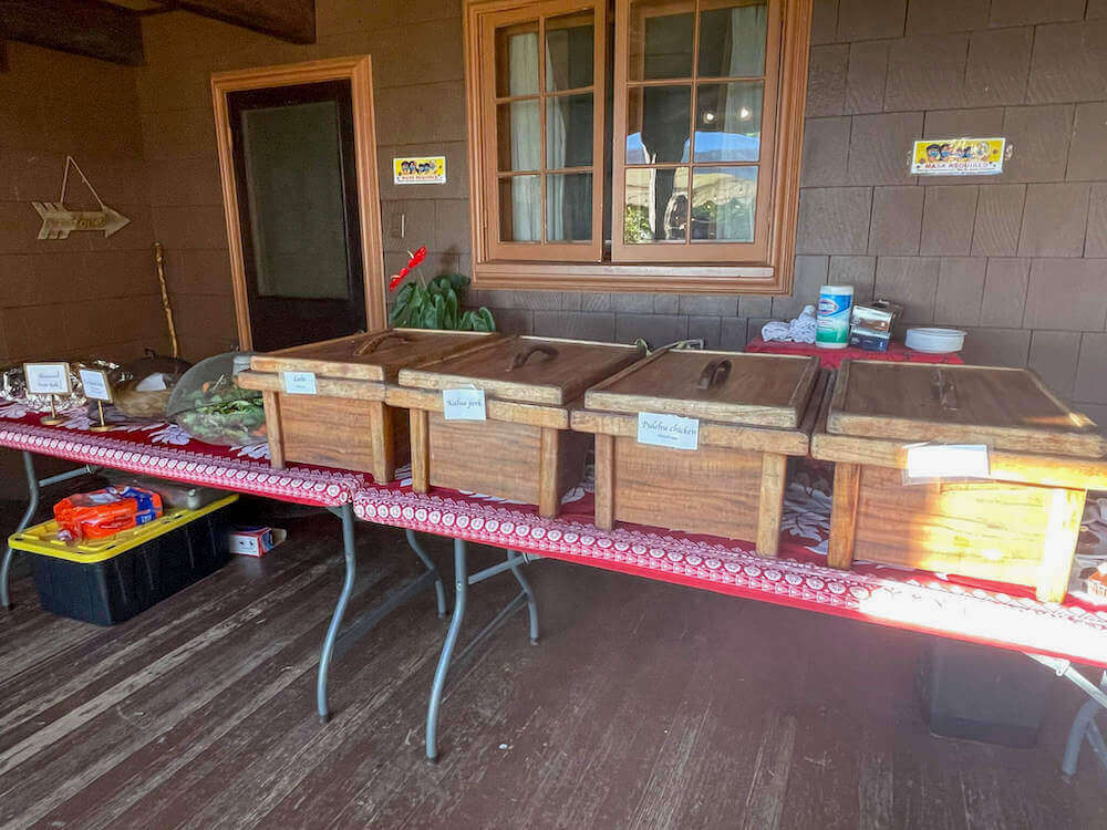 Nutridge Luau has incredible Hawaiian food. Image of Hawaiian food in wooden boxes on a table.