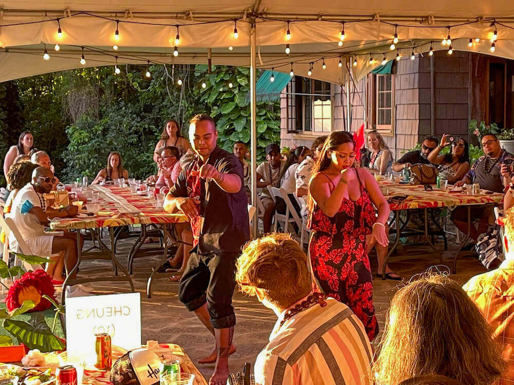 Image of a male and female hula dancer performing in an outdoor tent.