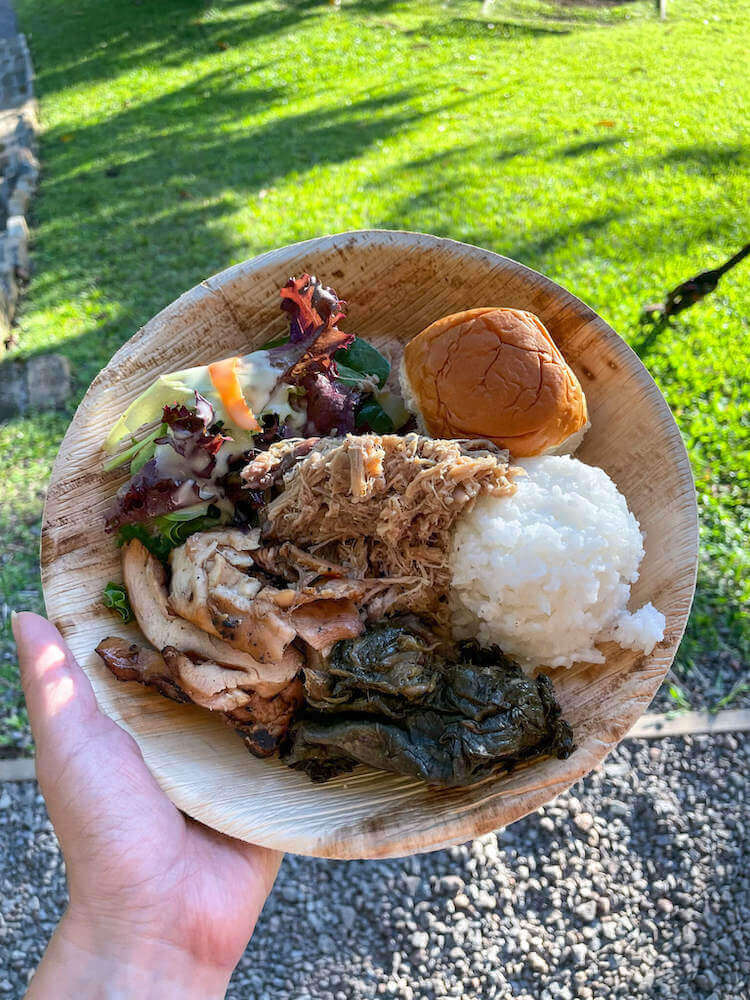 Try traditional Hawaiian food at Nutridge Luau on Oahu. Image of a plate with chicken, kalua pork, rice, salad, and more.