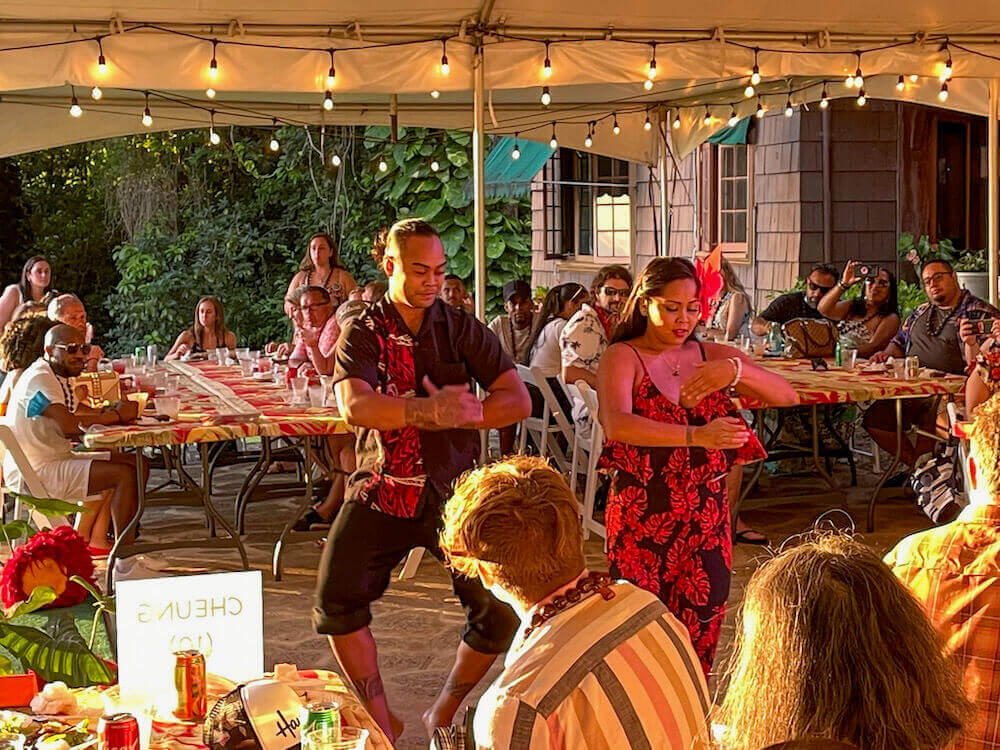 Image of a man and woman dancing in the middle of a tent filled with guests eating dinner.