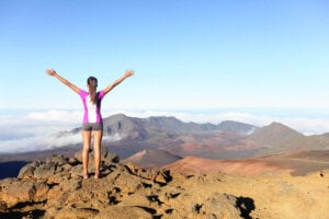 Find out the best Haleakala tours on Maui recommended by top Hawaii blog Hawaii Travel with Kids. Image of a woman standing on the summit of Haleakala Crater at Haleakala National Park.