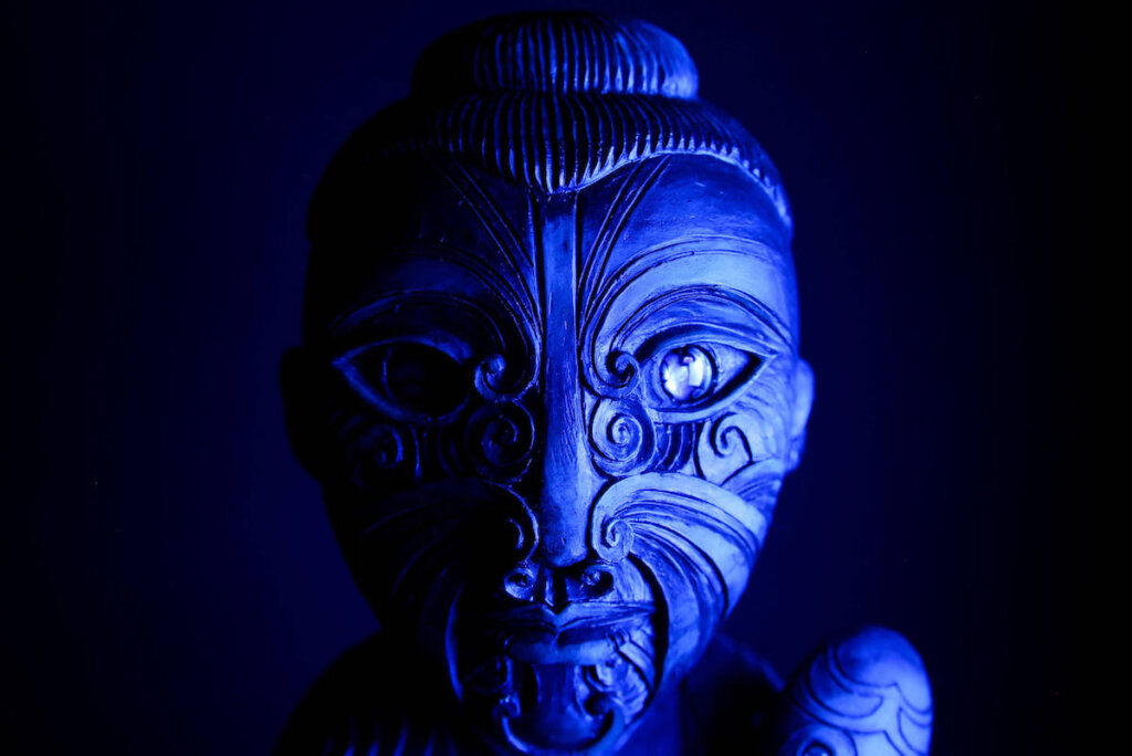 Find out the most haunted places in Hawaii worth checking out by top Hawaii blog Hawaii Travel with Kids. Image of a Polynesian mask with creepy blue lighting on it.