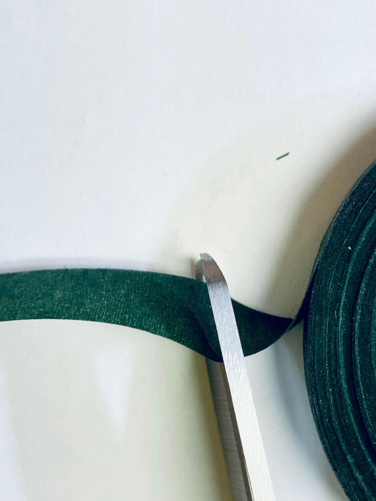 Image of scissors cutting a piece of green floral tape.