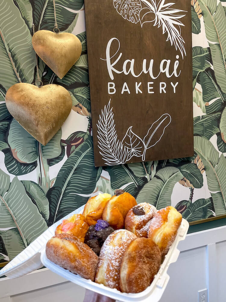 Named the best malasadas in Hawaii, Kauai Bakery offers an assortment of filled malasadas. Image of a takeout container filled with malasada donuts.