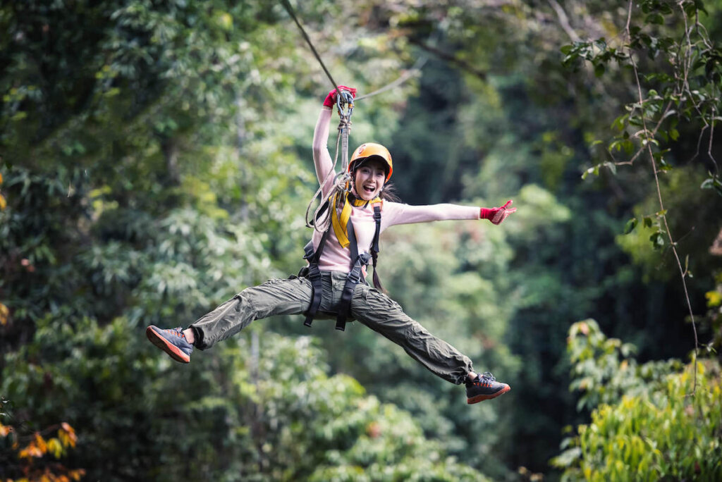 Find out the best Kauai zipline tours recommened by top Hawaii blog Hawaii Travel with Kids. Image of a woman wearing long sleeves and long pants ziplining in Hawaii.