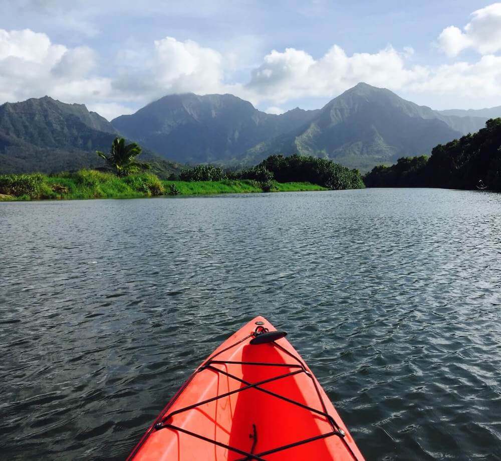 One of the top things to do in Hanalei for adventure seekers is to go kayaking Hanalei River. Image of a red kayak on Hanalei River in Kauai.
