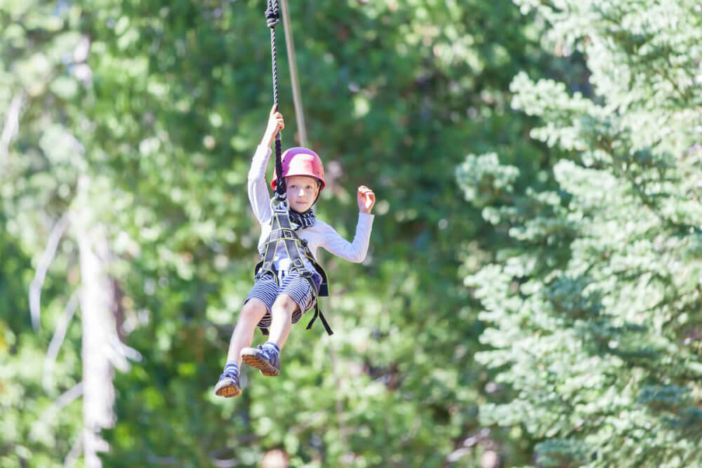 Find out where to go zip lining in Kauai by top Hawaii blog Hawaii Travel with Kids. Image of a boy ziplining in Hawaii.