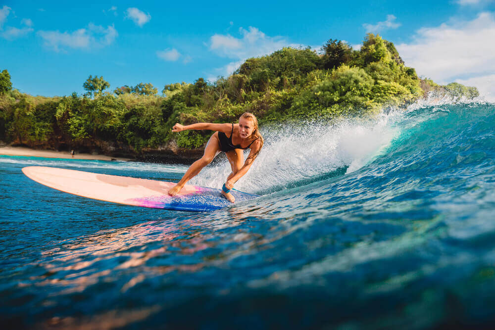 Find out the best Maui surfing lessons recommended by top Hawaii blog Hawaii Travel with Kids. Image of a woman surfing.